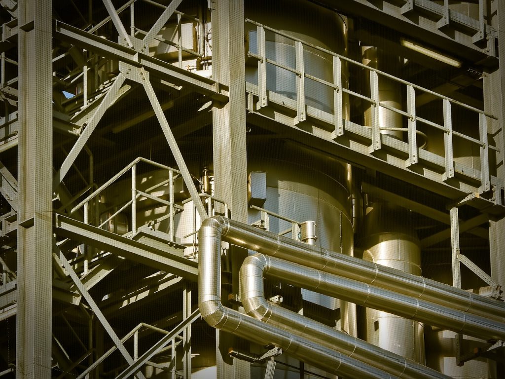 Vista de uma planta industrial metálica, com estruturas e edifícios de uma fábrica ao ar livre